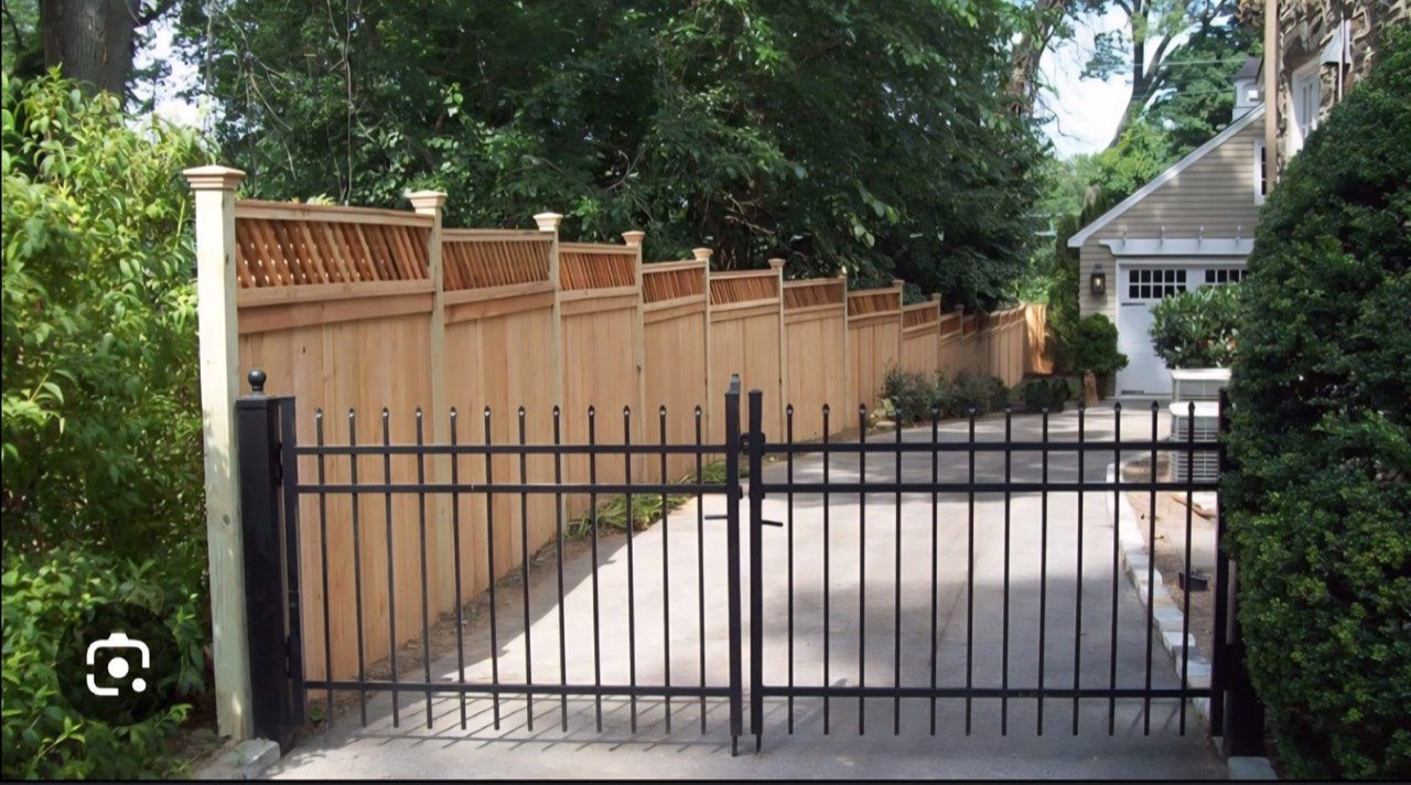 Black steel sliding gate beside a wooden fence