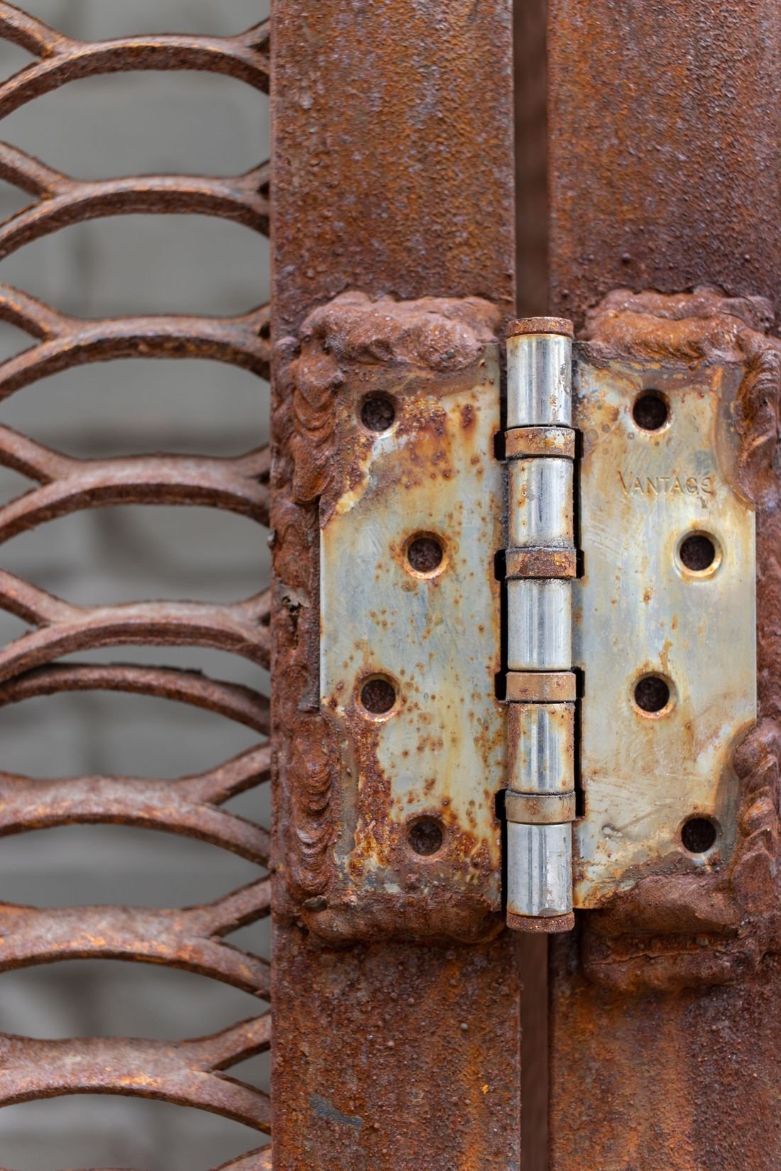Rusted steel hinge welded to a gate, ready for cleaning and repainting